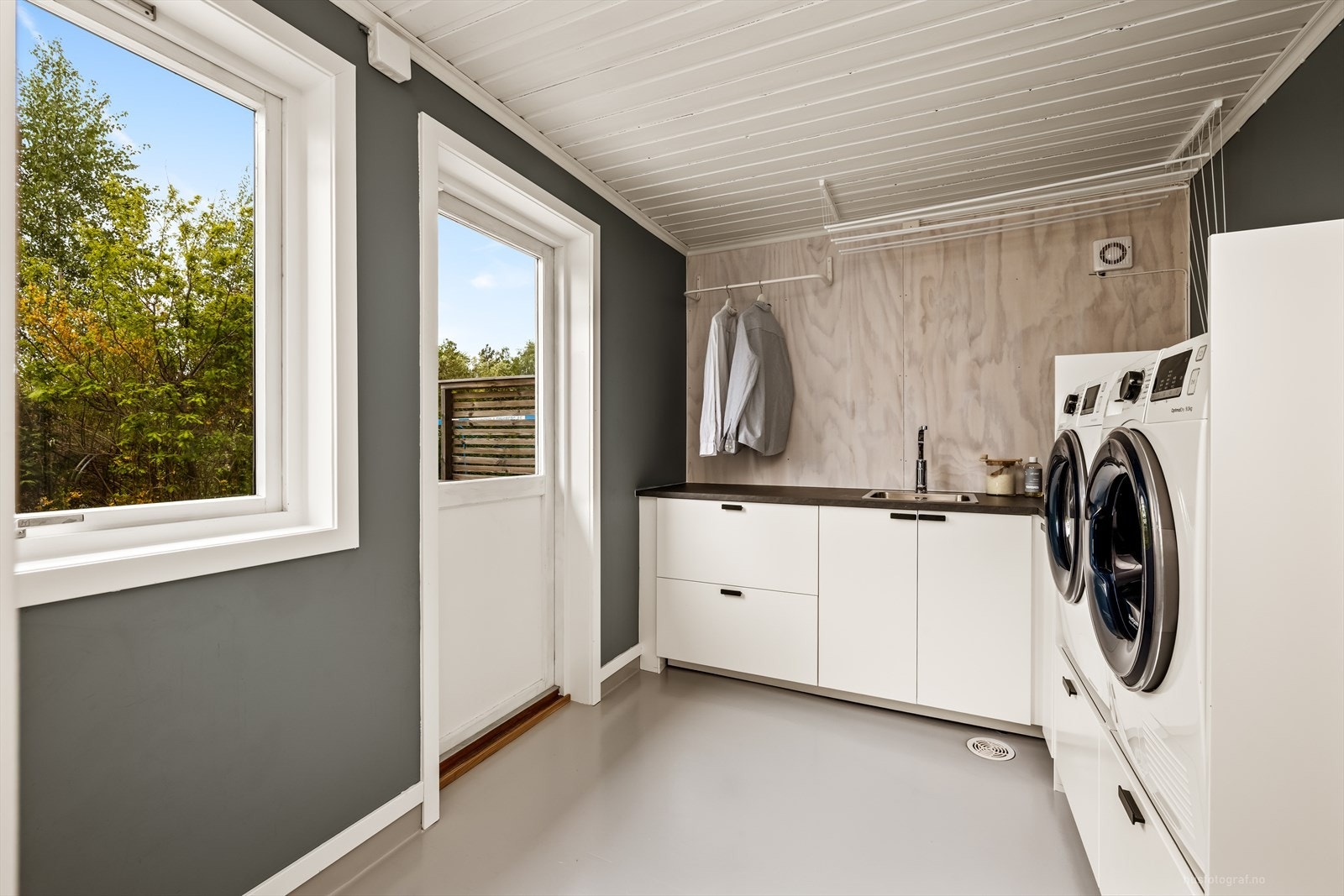 Et pent og praktisk vaskerom med innredning, opplegg for vaskemaskin og egen utgang. Galleribilde
