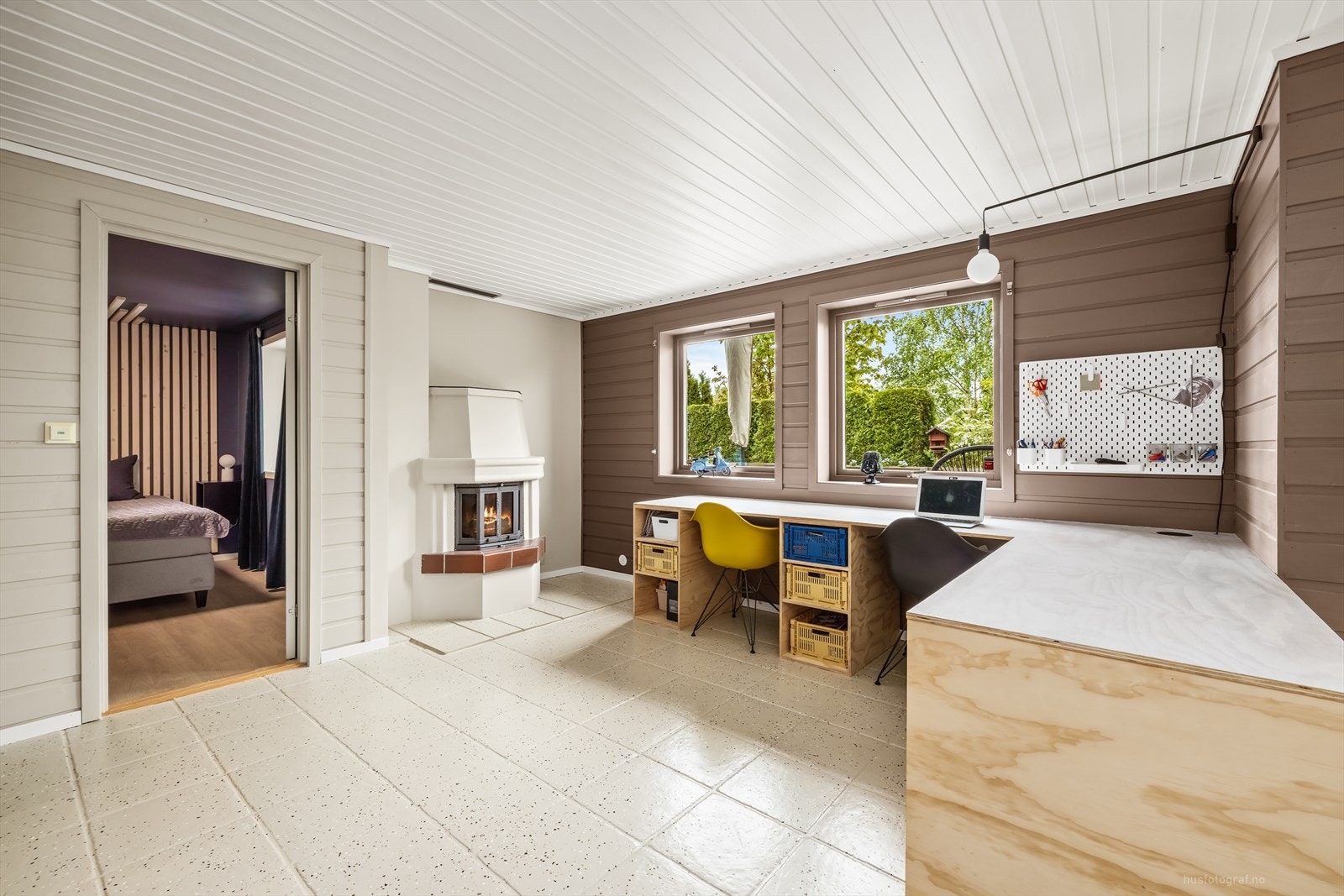 Rommet har en peis med innsats og overflater med malt trepanel og keramiske fliser. Galleribilde