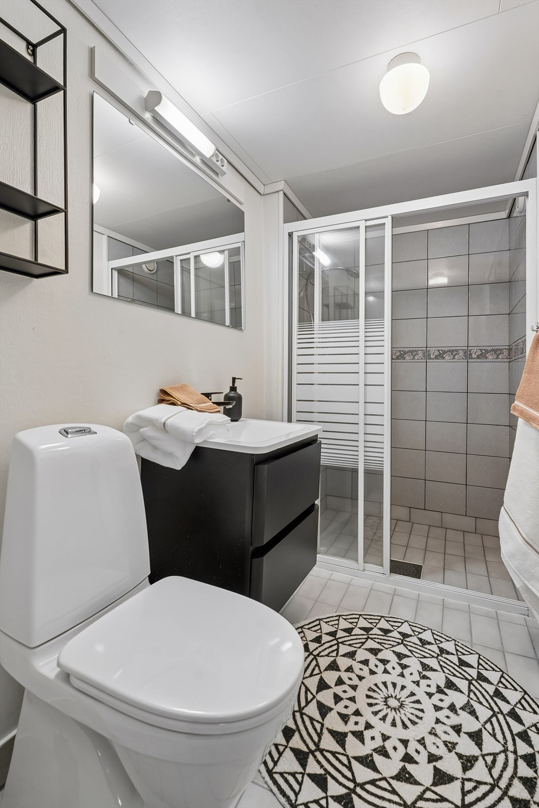 Lyst og delikat bad, innreidd med dusj på vegg, wc og servant. Galleribilde