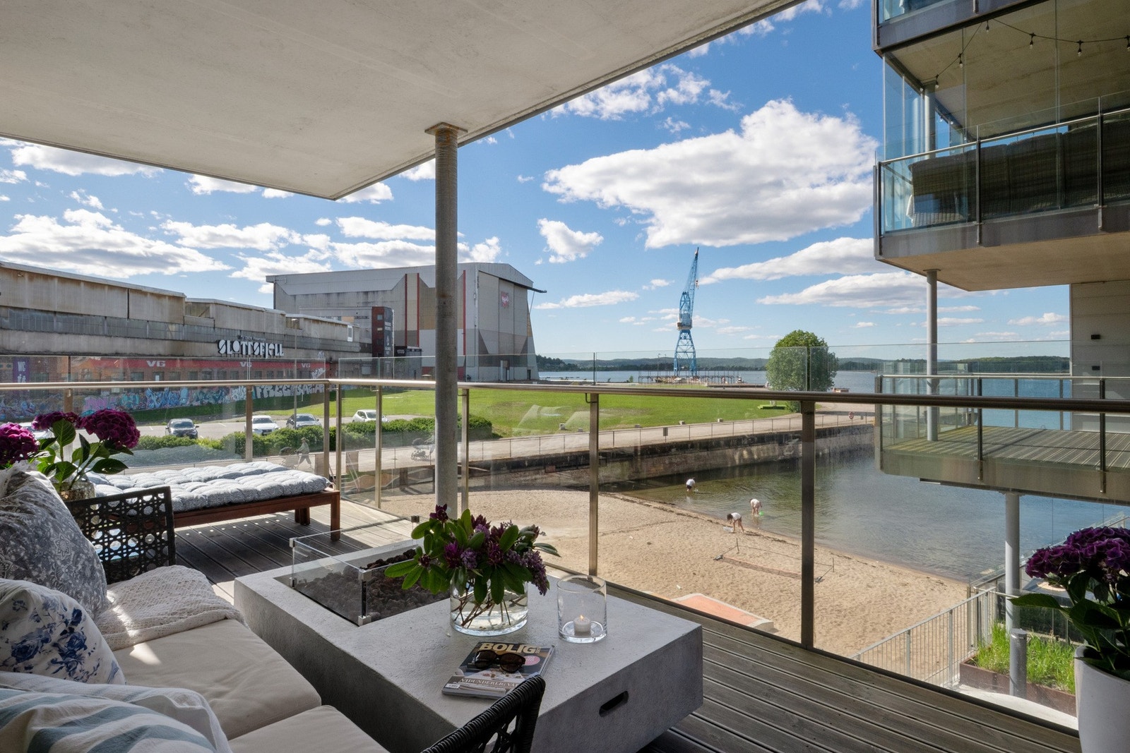 Balkongen har terrassebord på betongdekket, og det er montert utelys og utestikk på husveggen Galleribilde