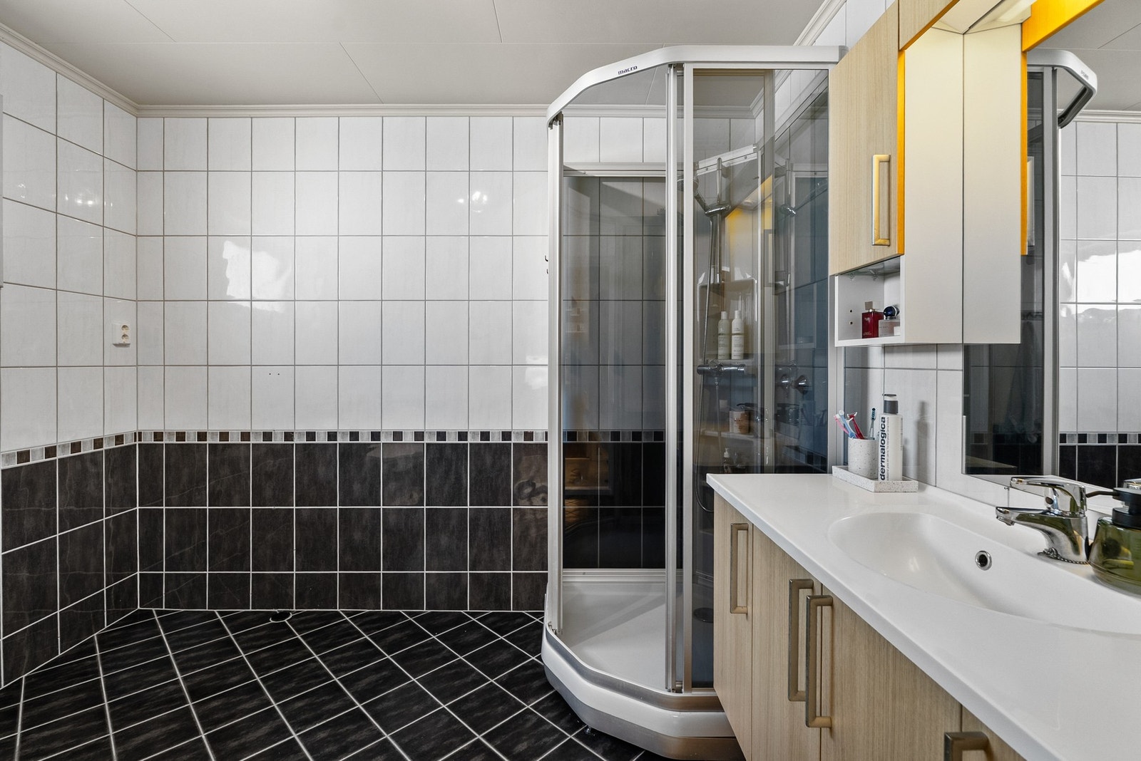 Badet i første etasje er flislagt og utstyrt med dusjkabinett og servantinnredning. Galleribilde