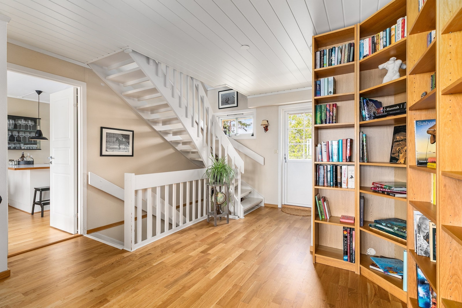 Gjennom etasjens hall kan morgenkaffen enkelt tas med fra kjøkkenet til altanen på baksiden. Hallen er åpen mot stuen og ble i 2013 oppgradert med ny himling. Galleribilde