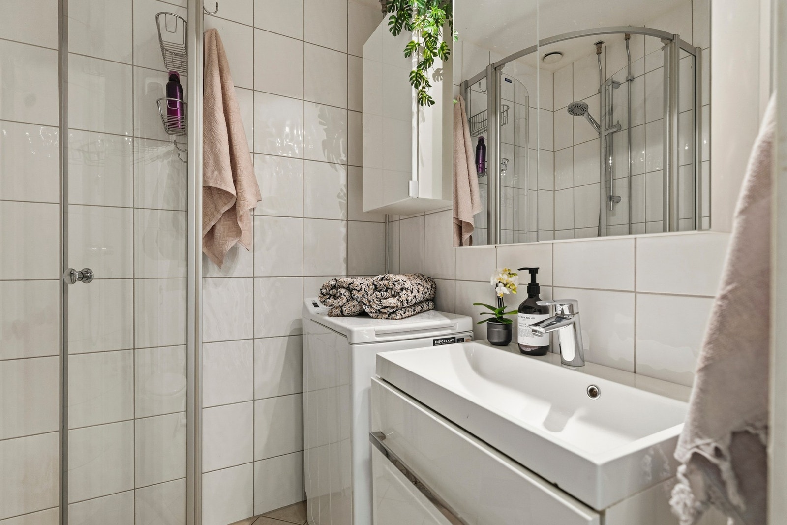Flislagt baderom fra 2010 med innredning bestående av servant med underskap, toalett, dusjhjørne med glassvegger og opplegg for vaskemaskin. Galleribilde