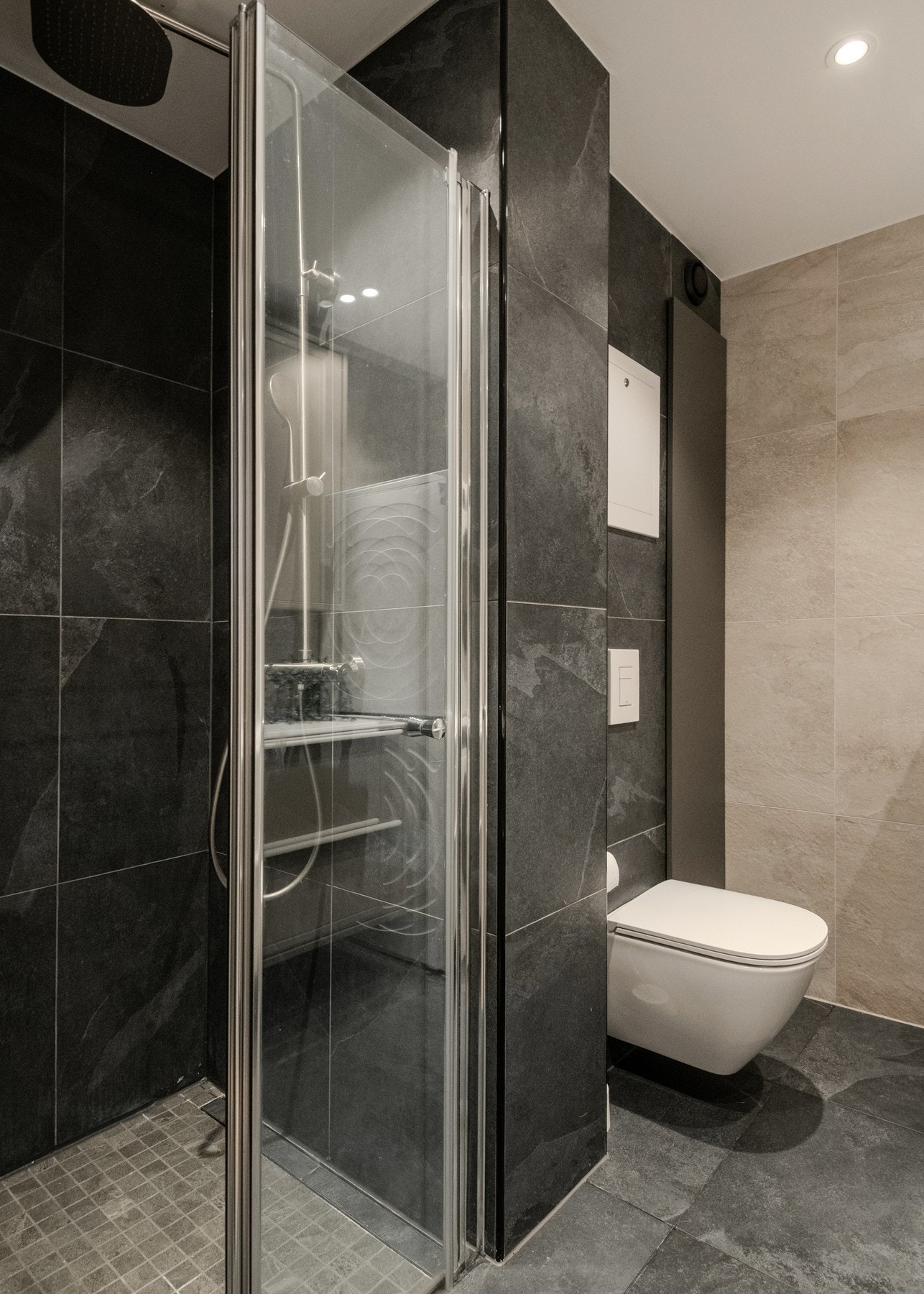 Badet er flislagt med varmekabler i gulv og mekanisk ventilasjon med avtrekk. Dusjhjørne med foldedør og stilren innredning gir et gjennomført uttrykk. Galleribilde