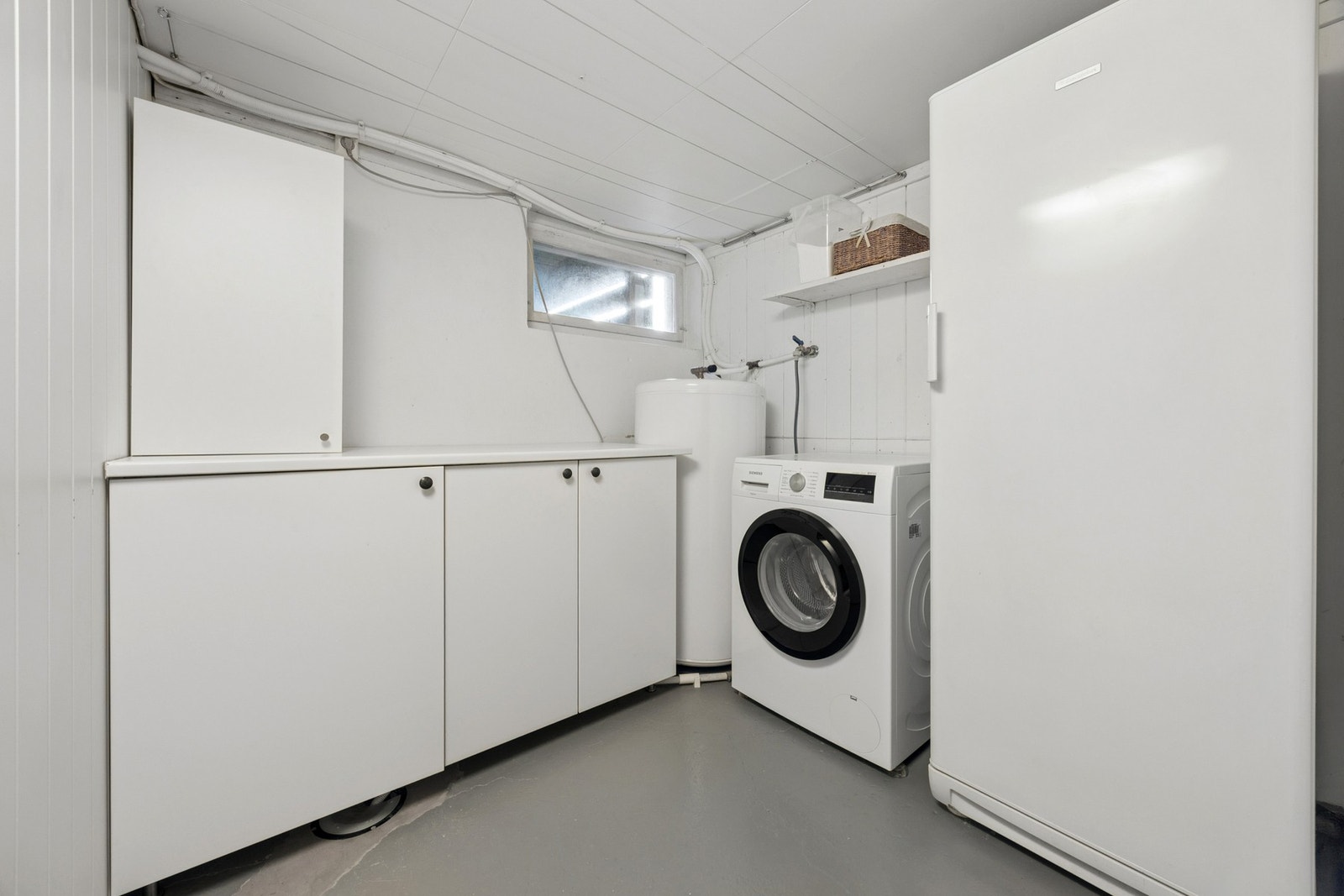 Eget vaskerom med opplegg for vaskemaskin, varmtvannsbereder og plass til oppbevaring. Galleribilde