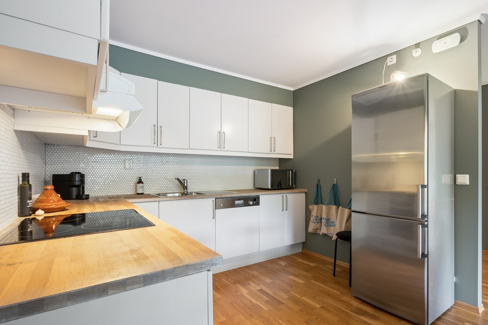 Kjøkkenet har en pen og tidløs Sigdal-innredning fra 2008 med hvite, glatte fronter og heltre benkeplate med nedfelt oppvaskkum i rustfritt stål. Galleribilde