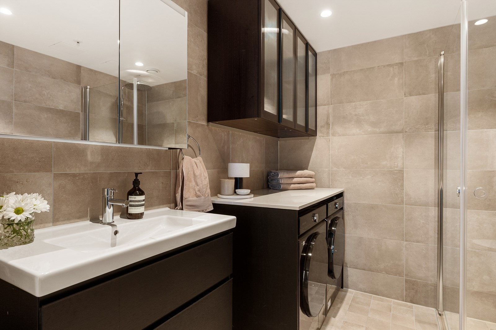 Badet har store, elegante fliser på vegger og gulv, kombinert med malt himling og downlights som gir et eksklusivt og behagelig uttrykk Galleribilde