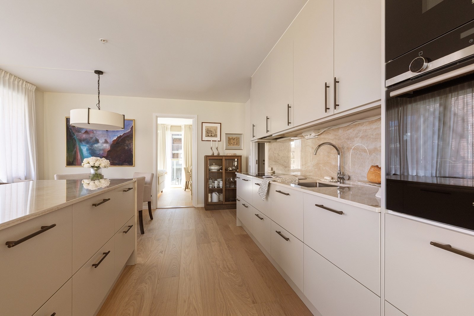 Den påkostede kjøkkenøya i Dekton-stein fungerer som boligens naturlige samlingspunkt, med både sitteplass, gode arbeidsflater og rikelig med oppbevaringsplass i skuffer Galleribilde