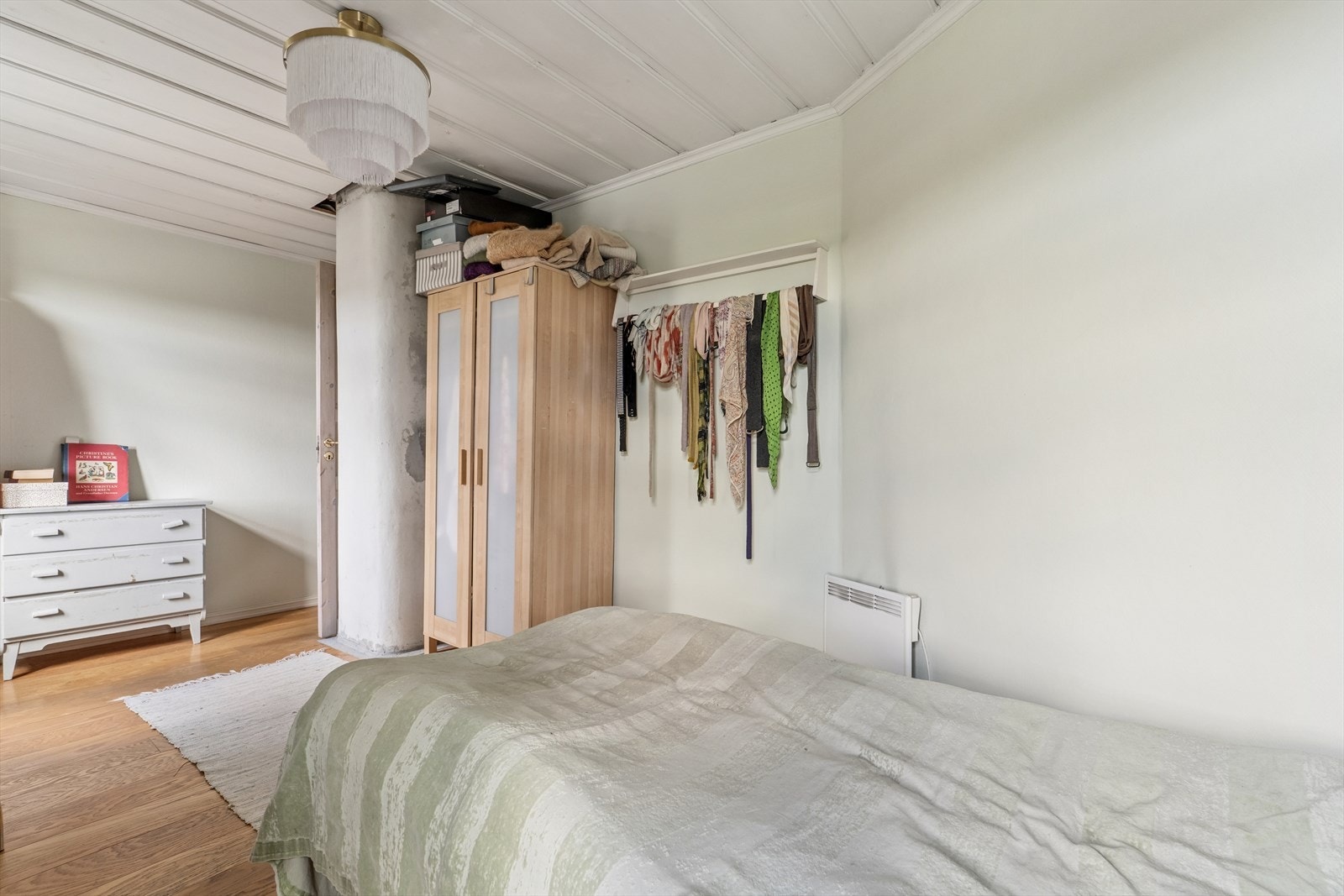 Soverom i eneboligen med synlig pipe og plass til seng og kommode. Galleribilde