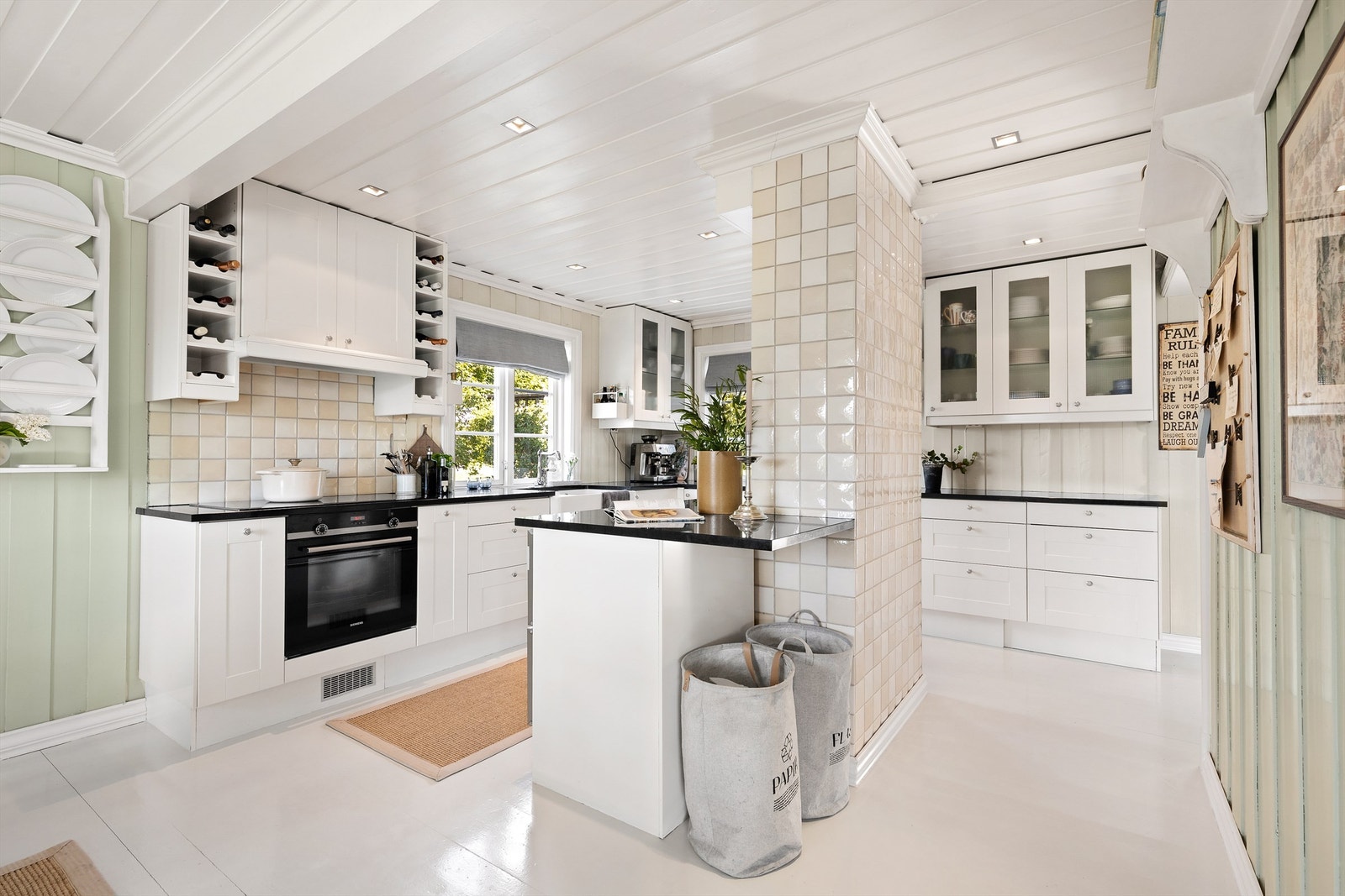 Kjøkken med gulvflate belagt med gulvbord av tre. Vegger med panel. Himling med panel. Nedsenket himling med downlights over deler av kjøkken. Galleribilde