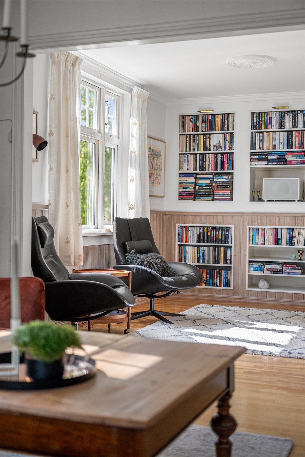 Veggene i stuen er kledd med en kombinasjon av tapet og trepanel. Galleribilde