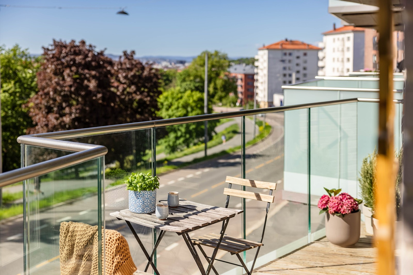 Balkongen er overbygget, har terrassebord på gulv og rekkverk av glass. Galleribilde
