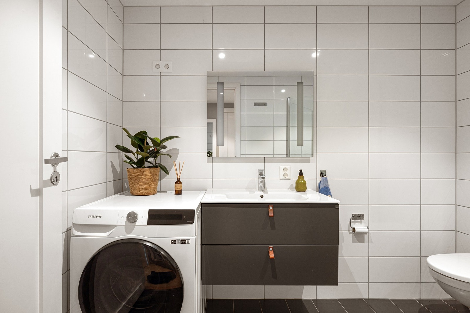 Leiligheten har et lyst og moderne flislagt baderom fra byggeåret 2017. Baderommet har mørke fliser på gulv med gulvvarme, lyse fliser på veggene, downlights i himlingen og mekanisk avtrekk. Galleribilde
