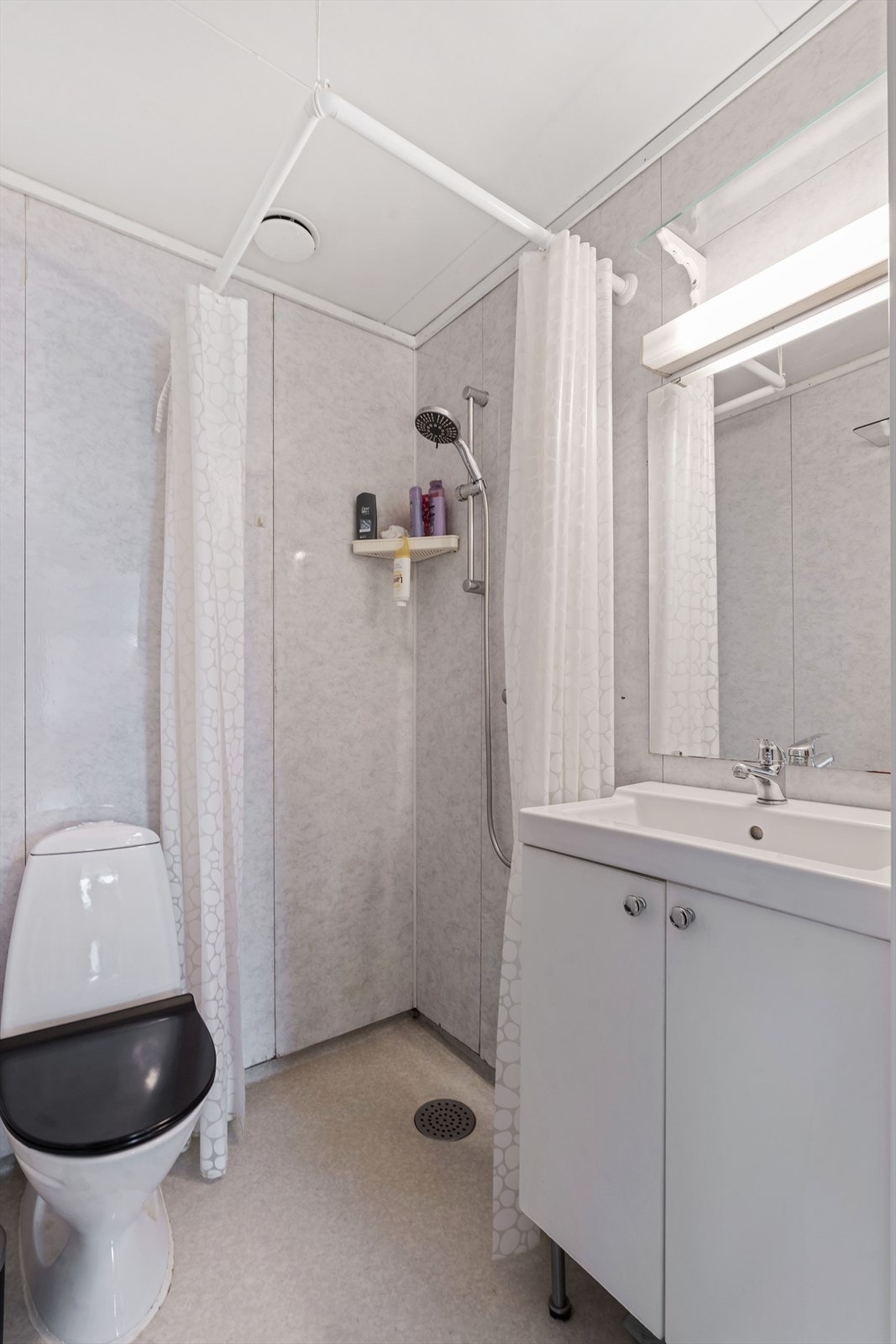 Badet i leiligheten har baderomsplater på veggene og vinylbelegg på gulvet fra 2018. Galleribilde