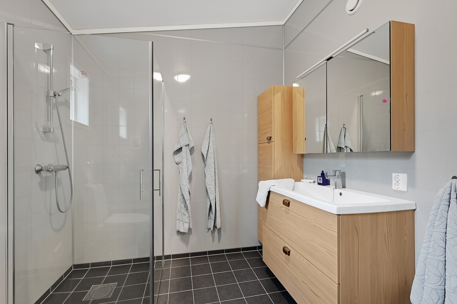 Bad i hovedetasjen med innredning fra Norema, toalett og dusjhjørne med glassvegger. Galleribilde