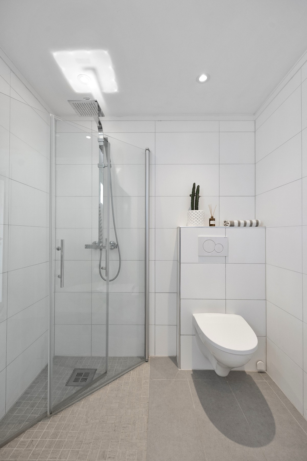 Badet er utstyrt med baderomsinnredning, veggmontert wc og dusjhjørne med innfellbare dører Galleribilde