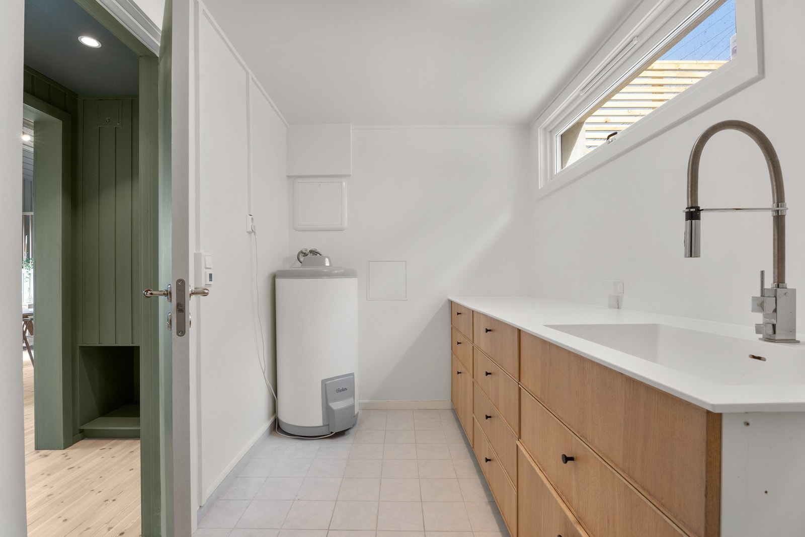 Vaskerommet er pent og praktisk innredet med en heldekkende, lys benkeplate med integrert vaskekum, benkeskap med trehvite skuffefronter, samt opplegg for vaskemaskin. Galleribilde