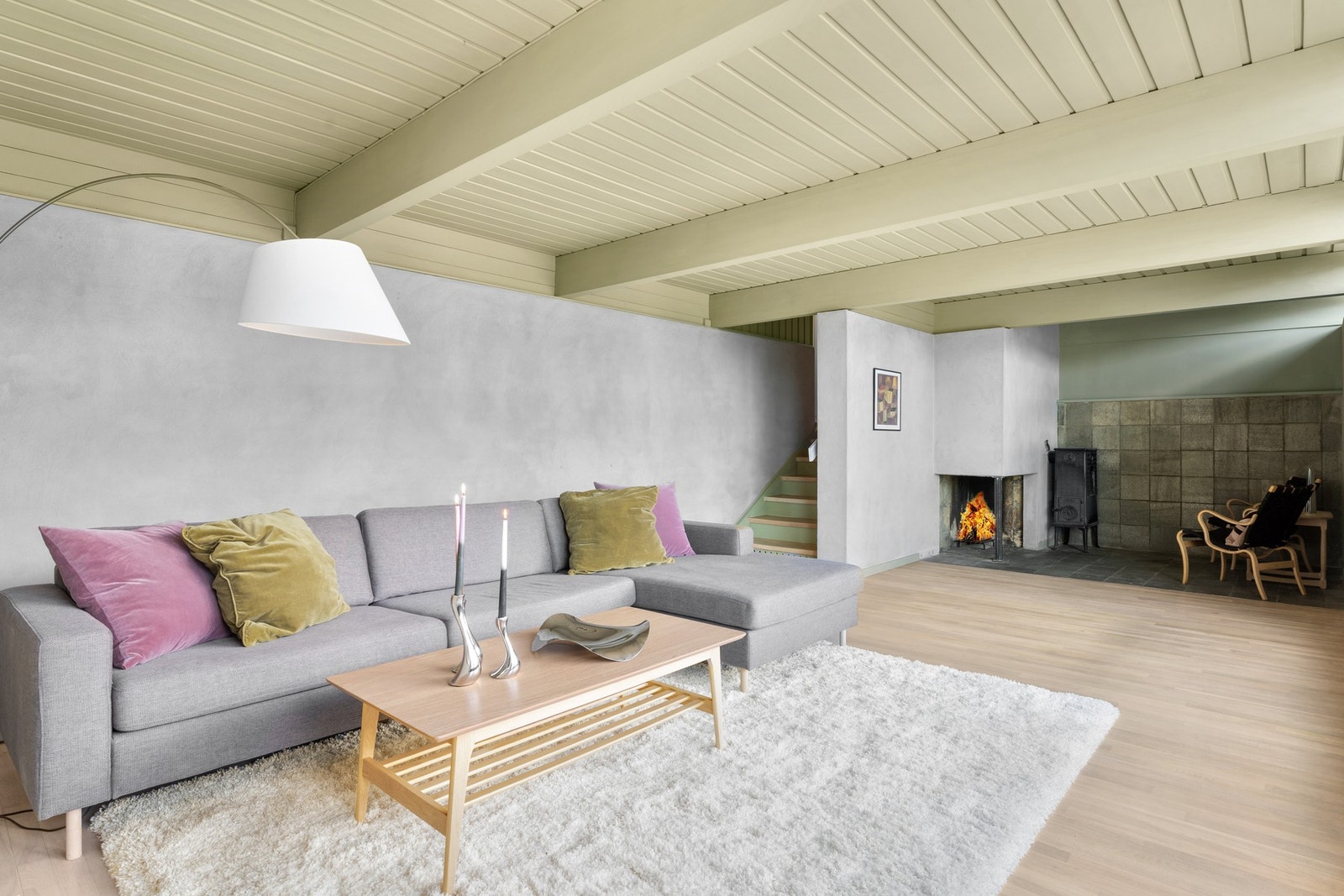 Kjellerstuen har lyst gulv, vegger i pusset mur, kombinert med glatte, malte flater og himling i malt panel med synlige dragere. Innerst i stuen er gulvet og deler av veggen flissatt. Galleribilde