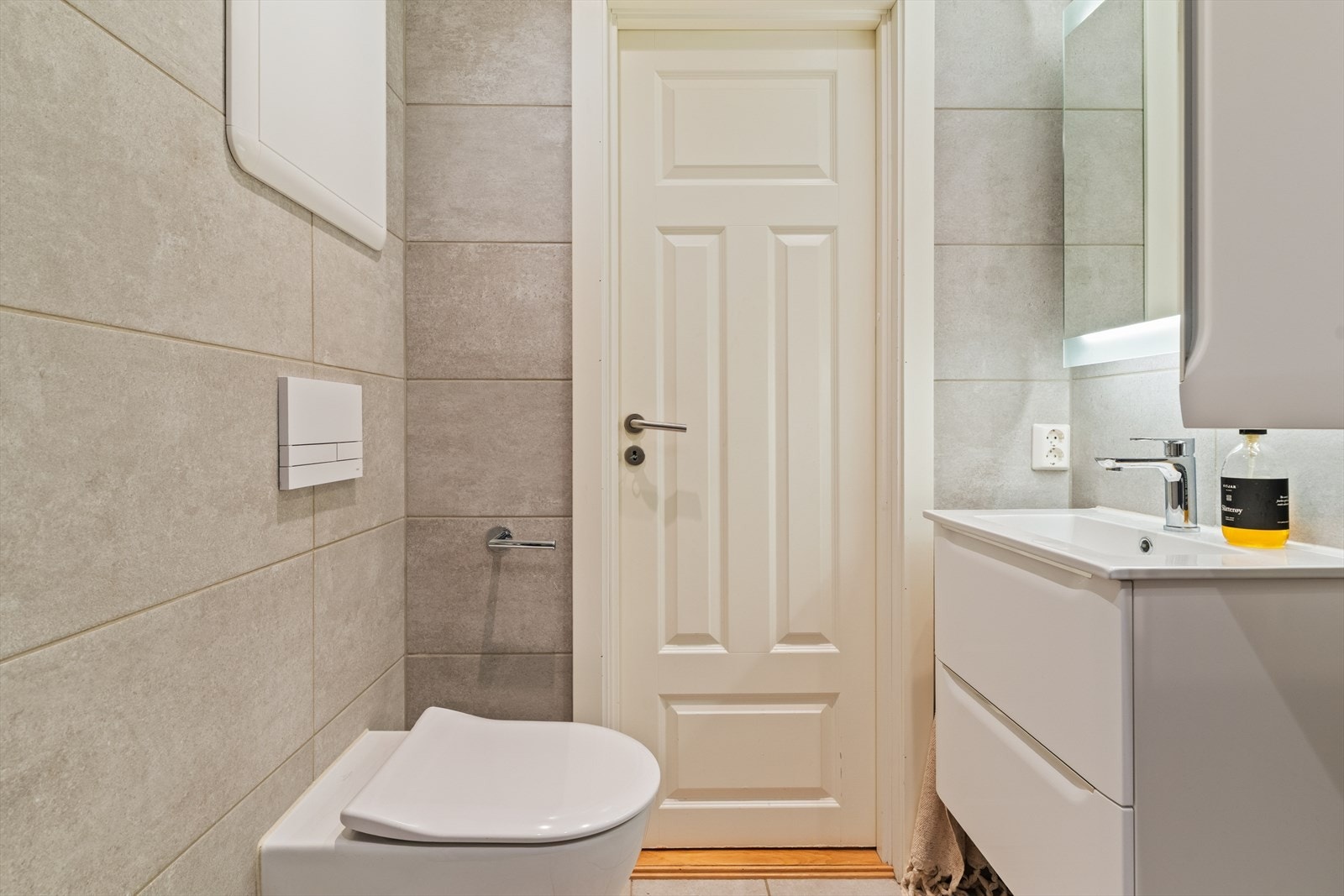 Badet inneholder baderomsinnredning med nedfelt servant, vegghengt toalett, dusjvegger og opplegg for vaskemaskin Galleribilde