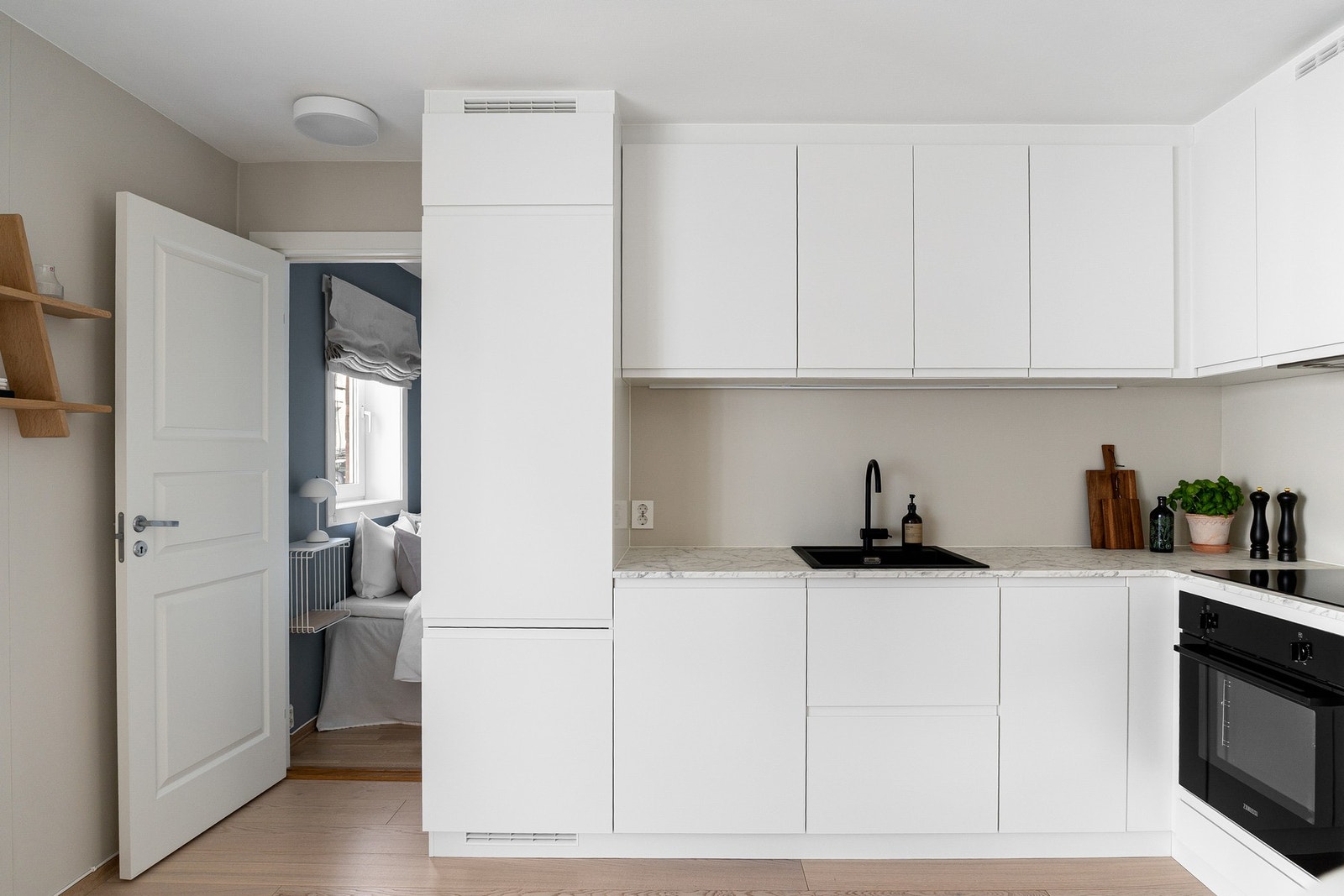 Innredningen byr på glatte, folierte fronter, laminat benkeplate med nedfelt kum i kompositt/plast, lyslist under overskap og glatt, malt vegg over benkeplaten. Galleribilde