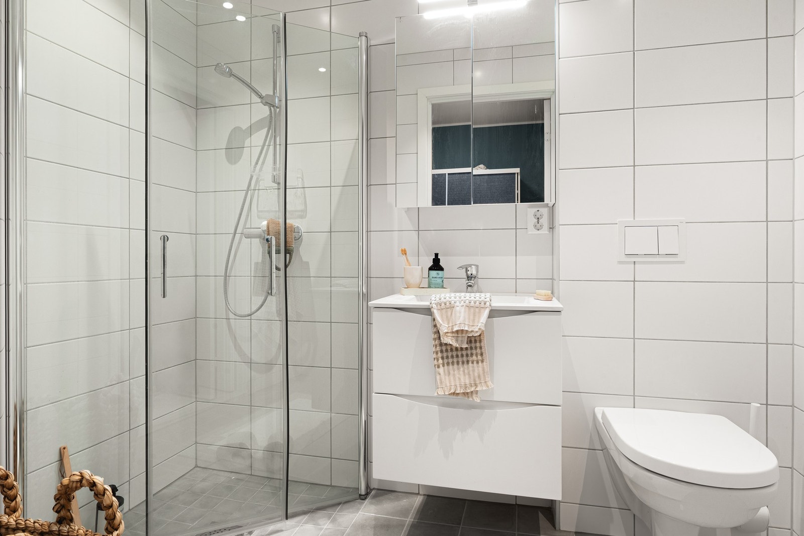 Badet i hovedetasjen er på 3,7 kvm og fremstår moderne og delikat med helflisede overflater, innfelte downlights og varmekabler i gulv. Badet er innredet med dusj med glassvegg, vegghengt toalett og baderomsinnredning med gode oppbevaringsmuligheter. Galleribilde