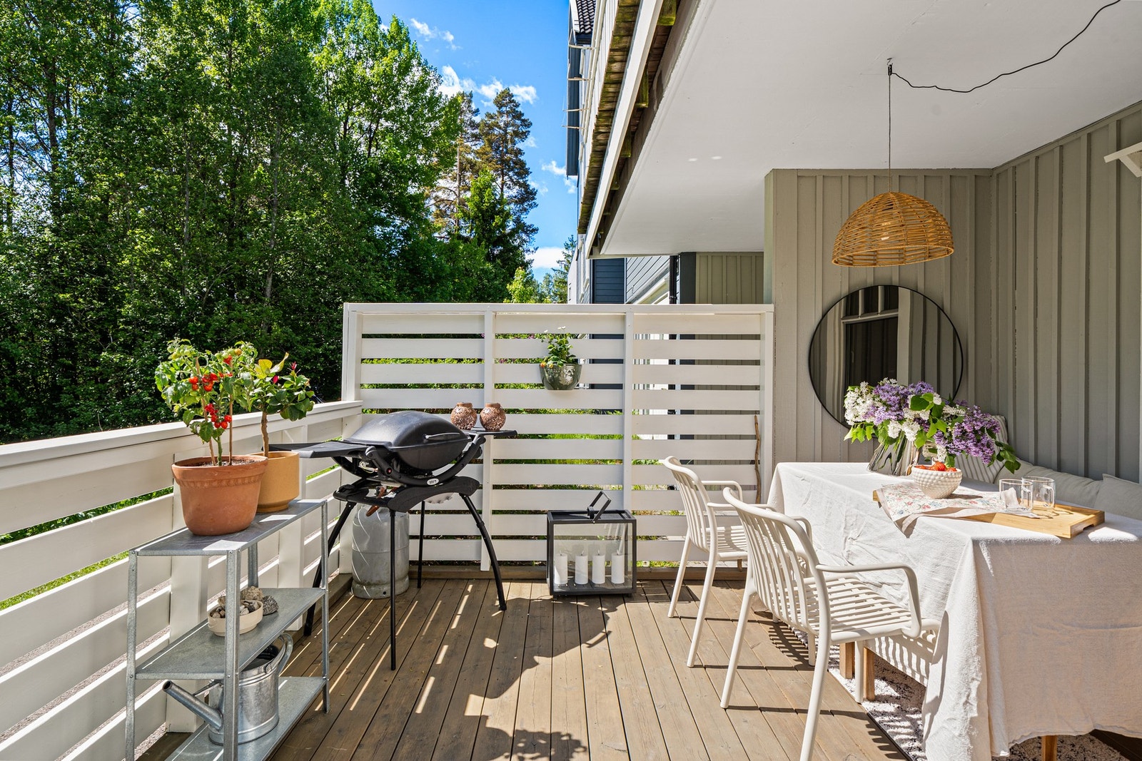 Romslig terrasseareal med plass til både grilling og middag i det fri - omgitt av frodig grønt og blå himmel. Galleribilde