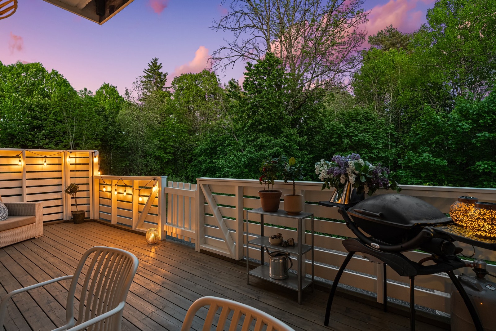 Terrassen i skumringen med utsikt mot skogen - grillklar og dekorert med blomster, klar for en uforglemmelig sommerkveld. Galleribilde