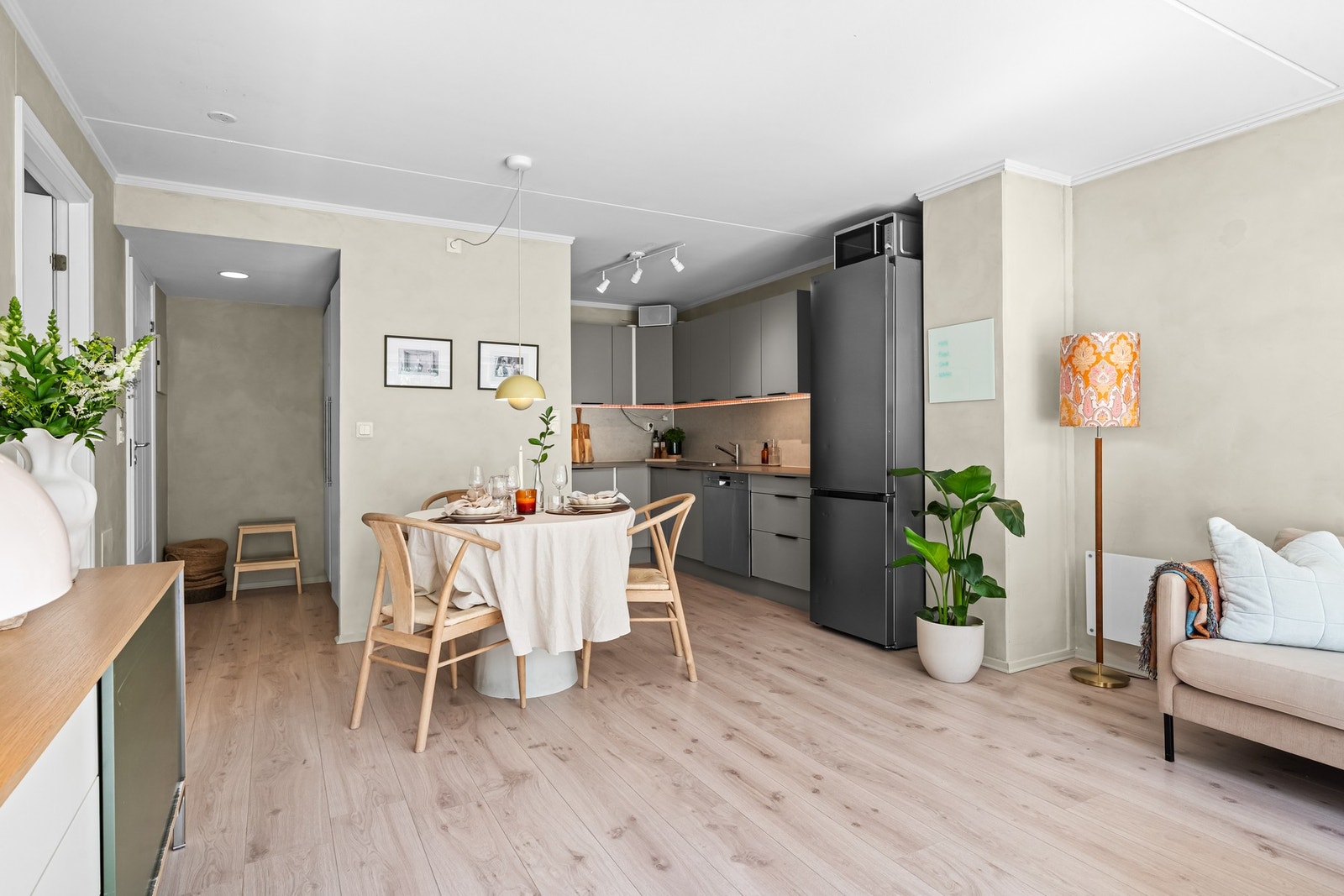 Praktisk og gjennomtenkt planløsning med åpen kjøkkenløsning, spiseplass og stue i ett - moderne kjøkken med mørke fronter og kobberdetaljer gir et stilrent uttrykk. Galleribilde