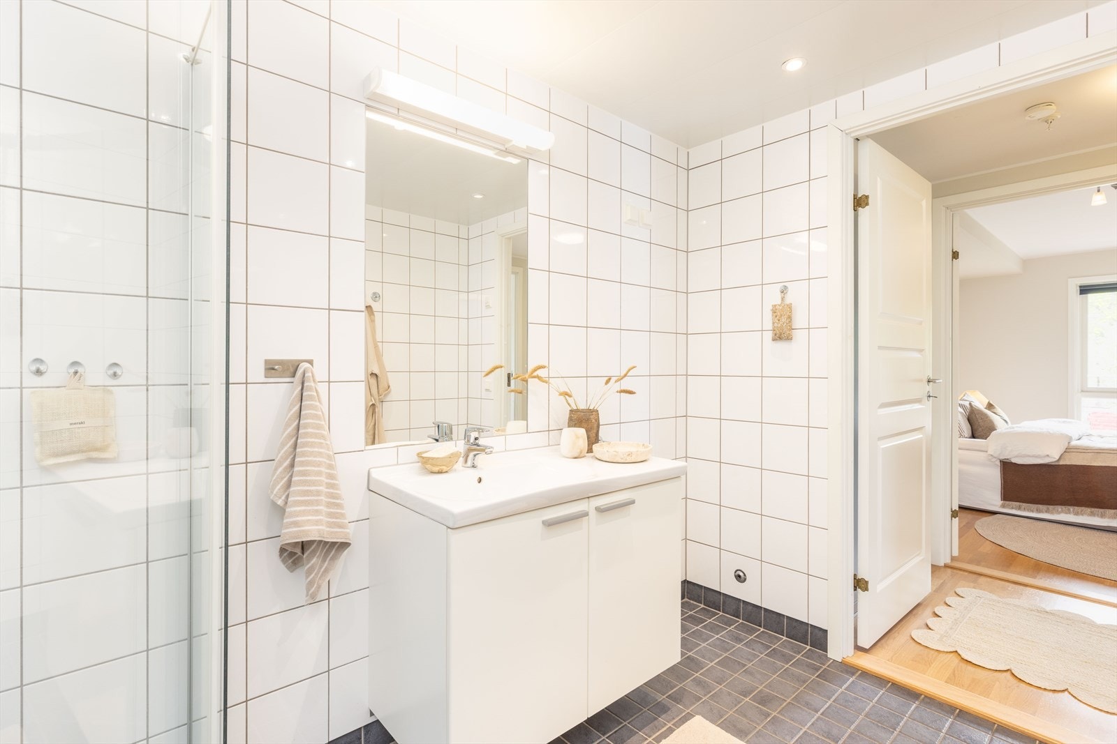 Det største badet er innredet med baderomsmøbel med slette fronter og heldekkende servant, innfliset speil, vegglampe, vegghengt toalett samt buet dusjhjørne med dusjgarnityr og hånddusj, i tillegg til opplegg for vaskemaskin. Galleribilde