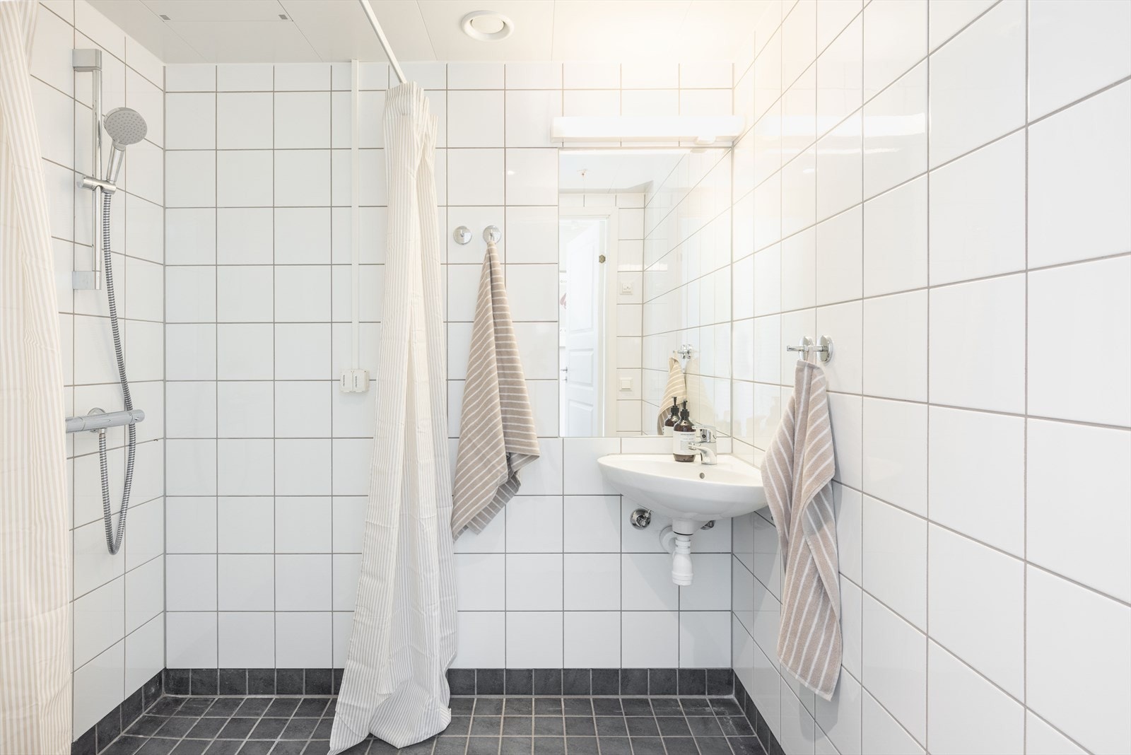 Begge badene har keramiske fliser på gulv og vegger, metallplater i himling med innfelte spotter og gulvvarme. Galleribilde