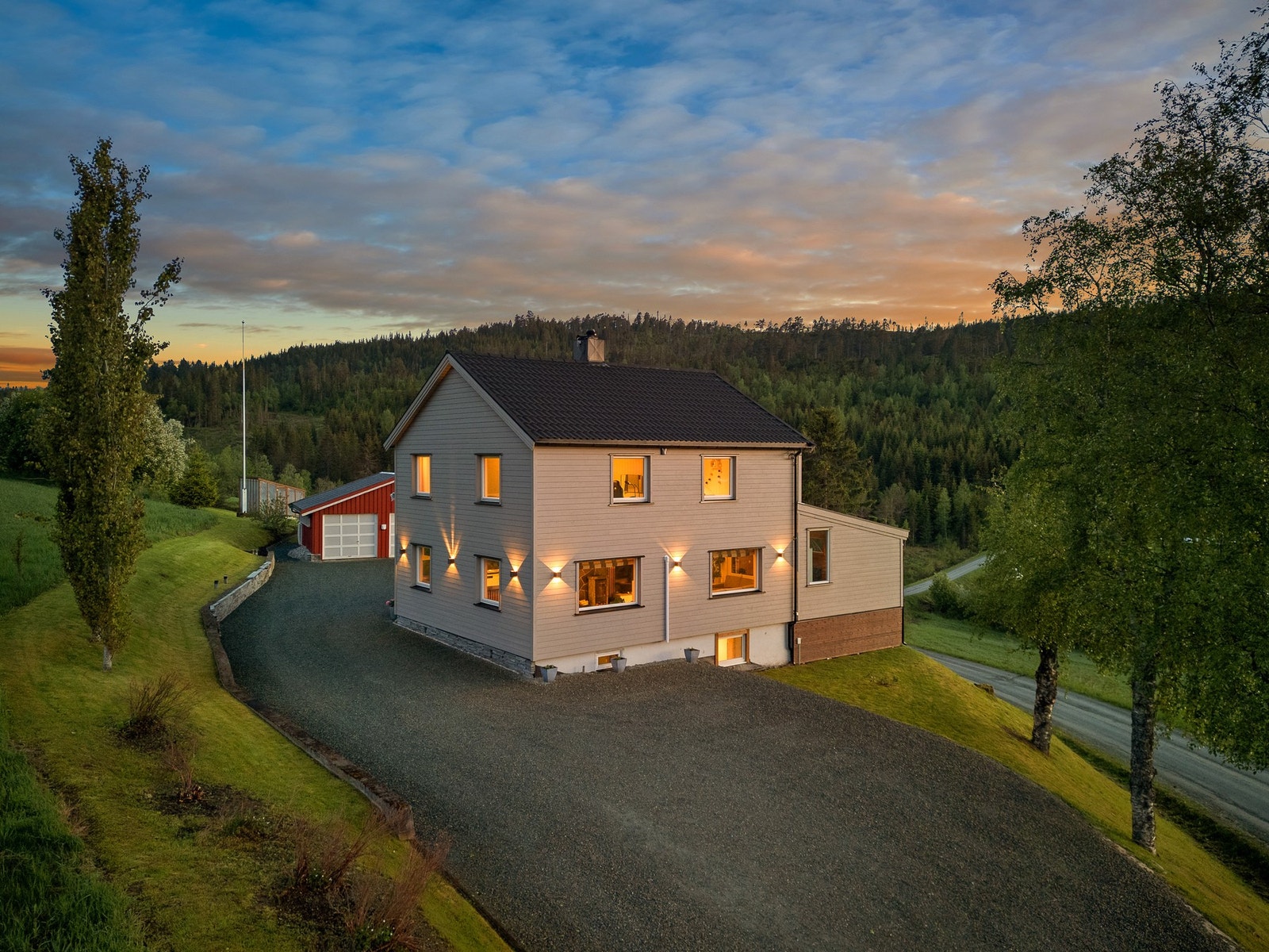 Eiendommen har en stor gruset gårdsplass med plass til flere biler og en garasje. Galleribilde