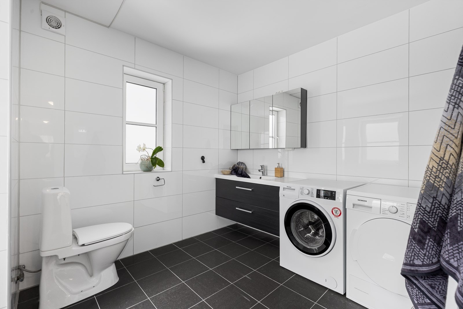 Badet er innredet med nedfelt servant, toalett, dusjhjørne og opplegg for vaskemaskin. Galleribilde