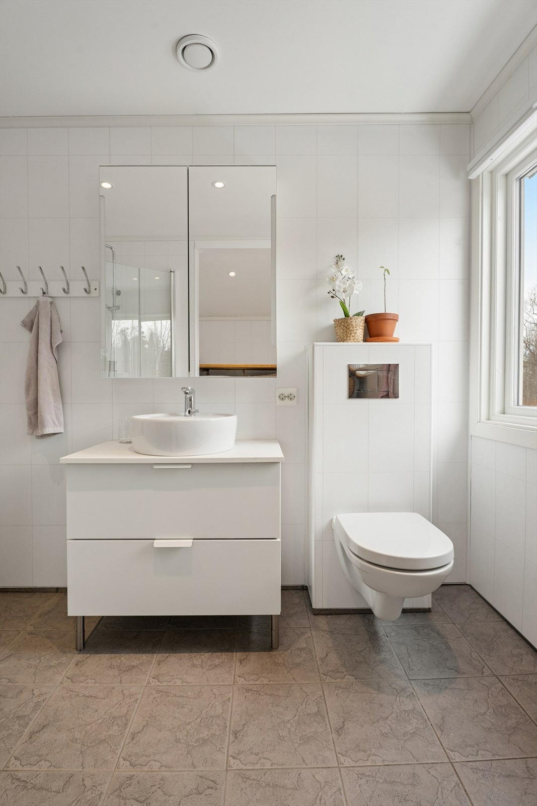 Bad/vaskerom som er oppgradert i 2017. Flislagt gulv, og lyse baderomsplater på vegg. Badet er innredet med servant med underskap, speilskap, dusjhjørne og veggmontert toalett. Galleribilde