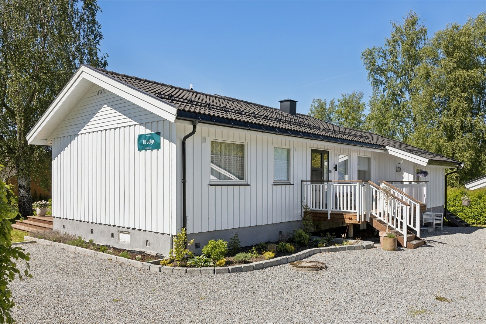 Enebolig over ett plan med tilhørende garasje. Hyggelig innkjørsel og inngangsparti med pent opparbeidet bed og terrasse med plass til en liten sittegruppe. Galleribilde