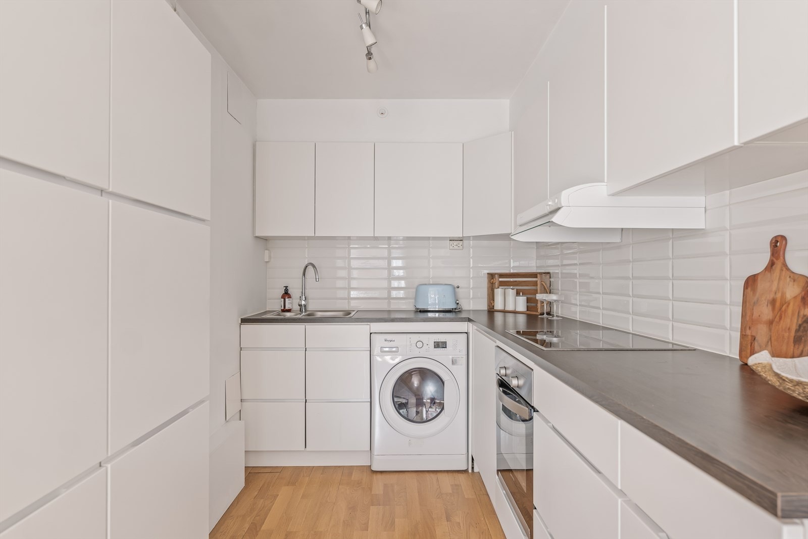 Kjøkkenet består av innredning med glatte, folierte fronter, laminat benkeplate med nedfelt kum i rustfritt stål og fliser på vegg over benk samt ventilator som er tilsluttet kanal. Galleribilde