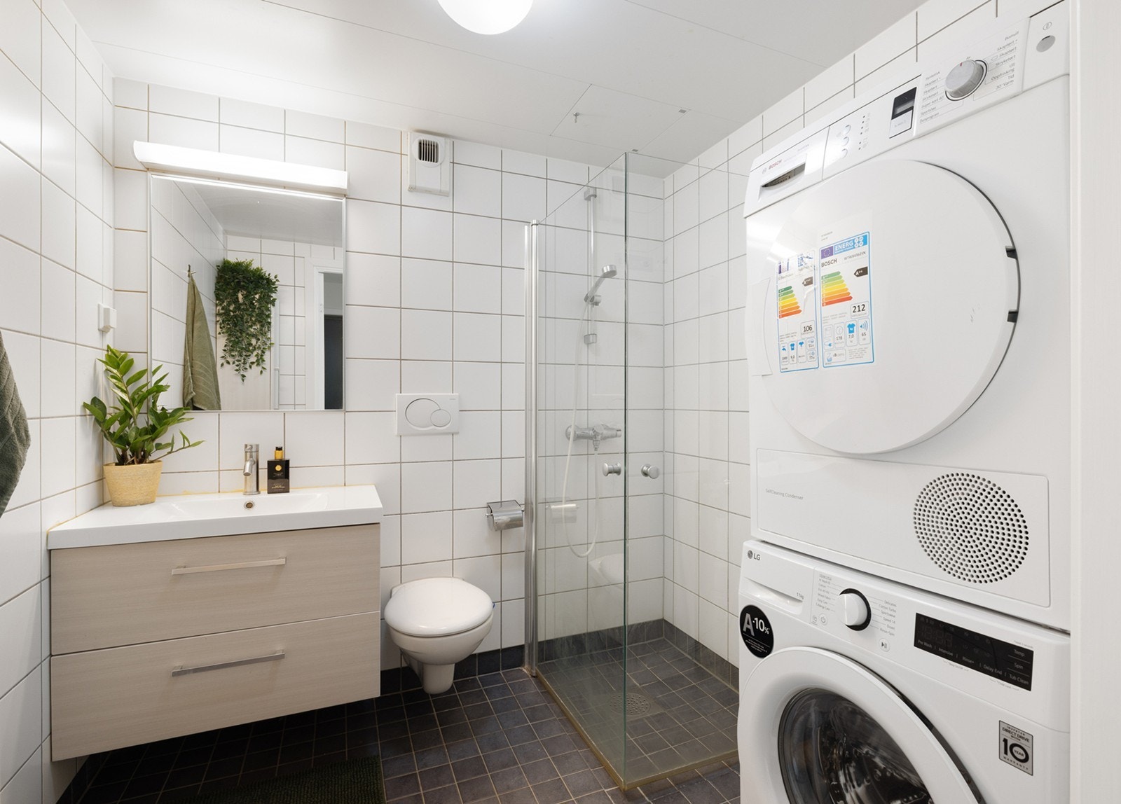 Badet har flislagte vegger og flislagt gulv med elektriske varmekabler. Baderomsinnredning med nedfelt servant, veggmontert toalett og dusjhjørne med glassvegger. Galleribilde