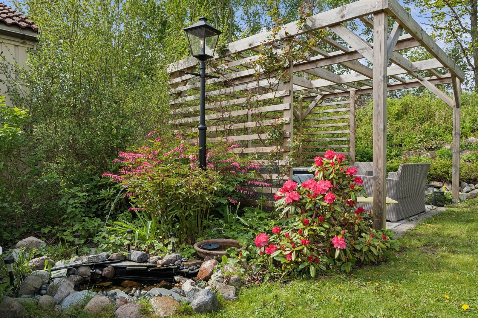 Frodig og stemningsfull hage med pergola omgitt av vakker beplantning og blomstrende detaljer - bare å nyte! Galleribilde