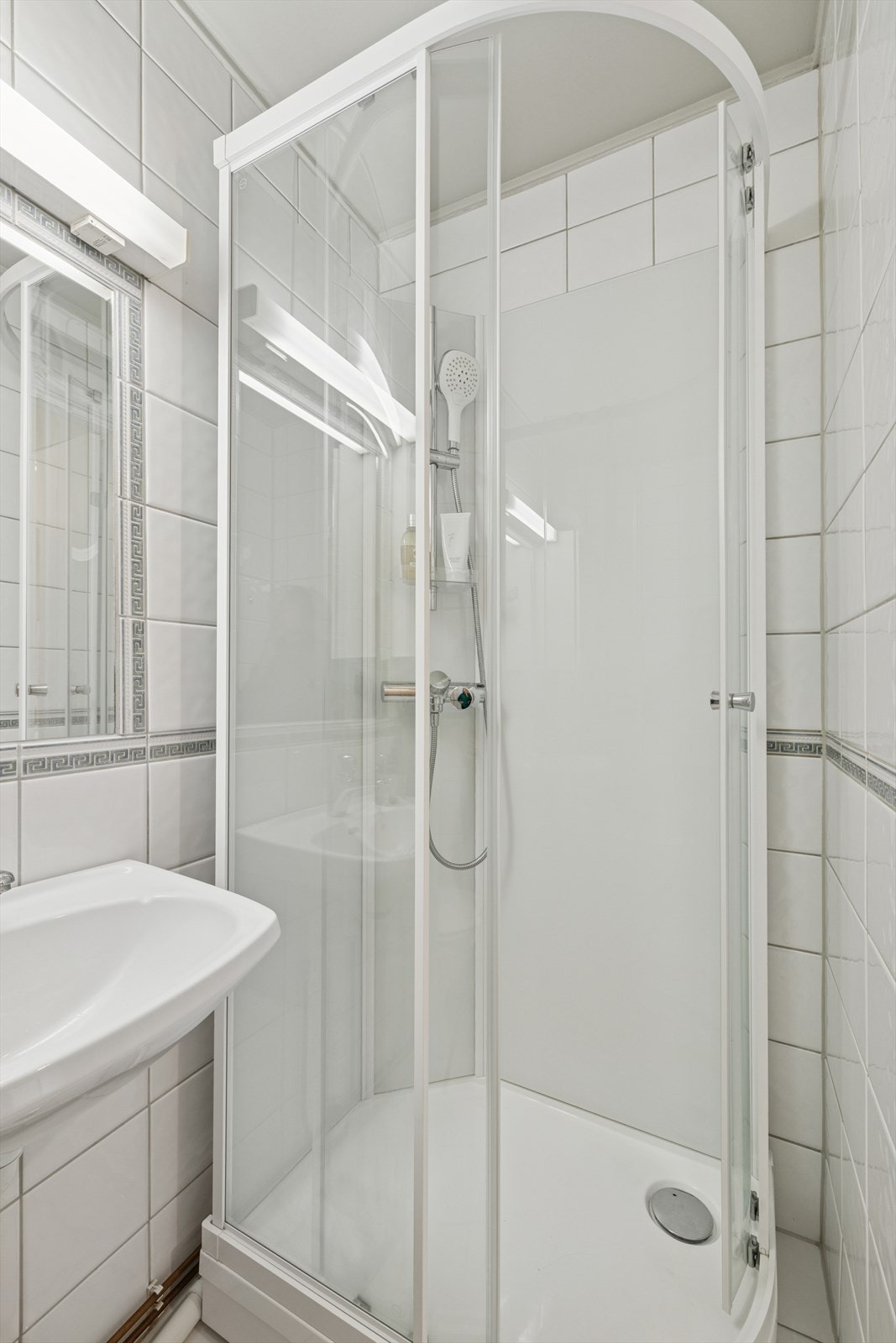 Badet er innredet med vegghengt servant med ett-greps blandebatteri, gulvstående toalett og dusjkabinett. Galleribilde