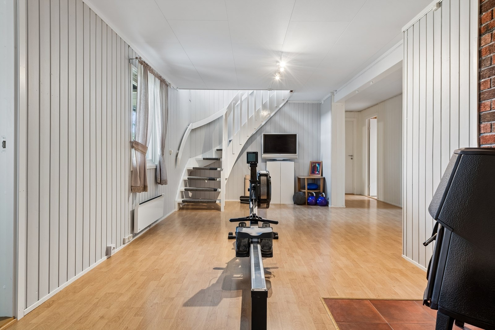 Romslig kjellerstue i sokkeletasjen med en eldre peisovn som varmekilde. Rommet er slått sammen med tidligere hall. Galleribilde