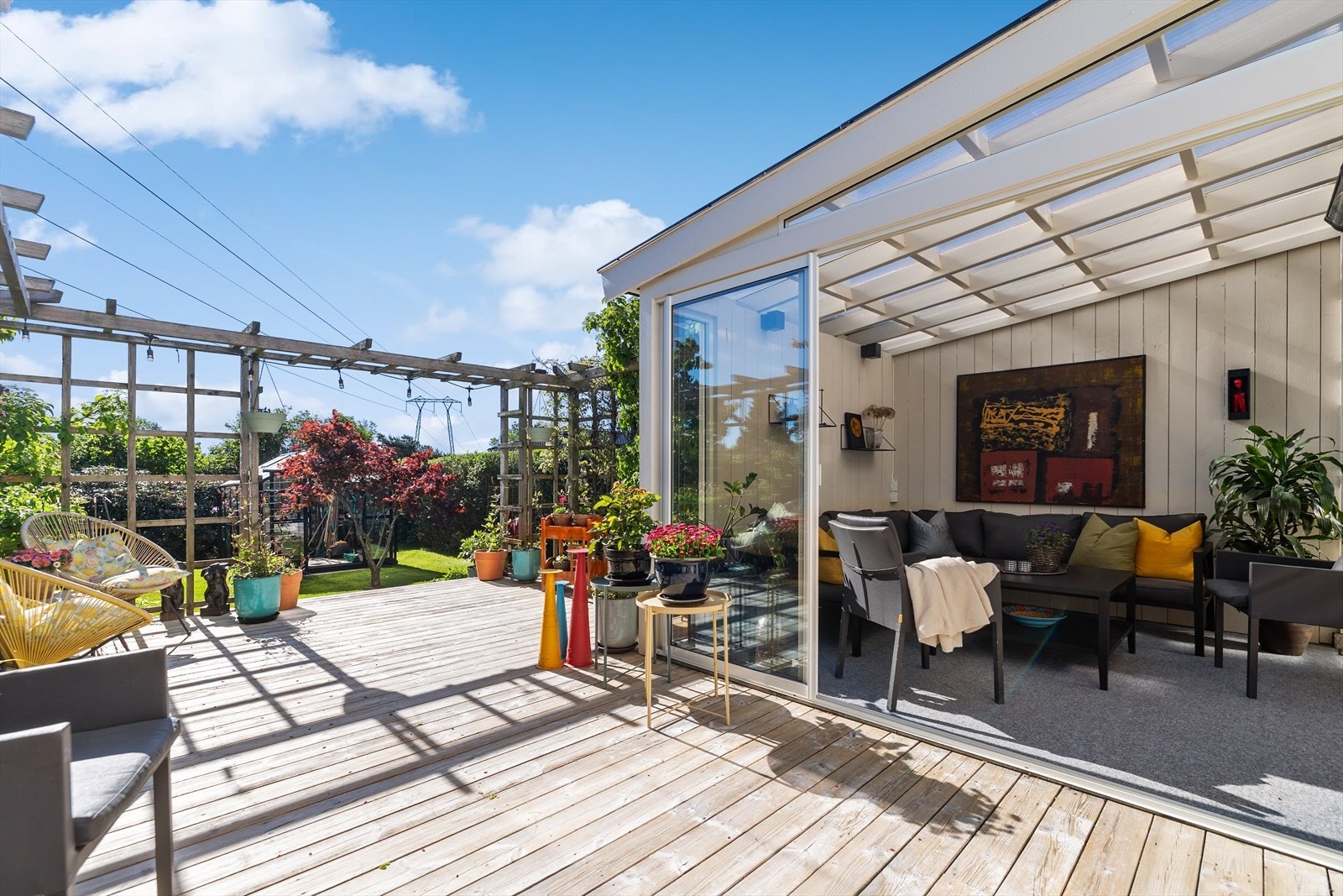 Hagestuen har god plass til sittegruppe og leder videre ut til en skjermet terrasse og den frodige hagen. Galleribilde