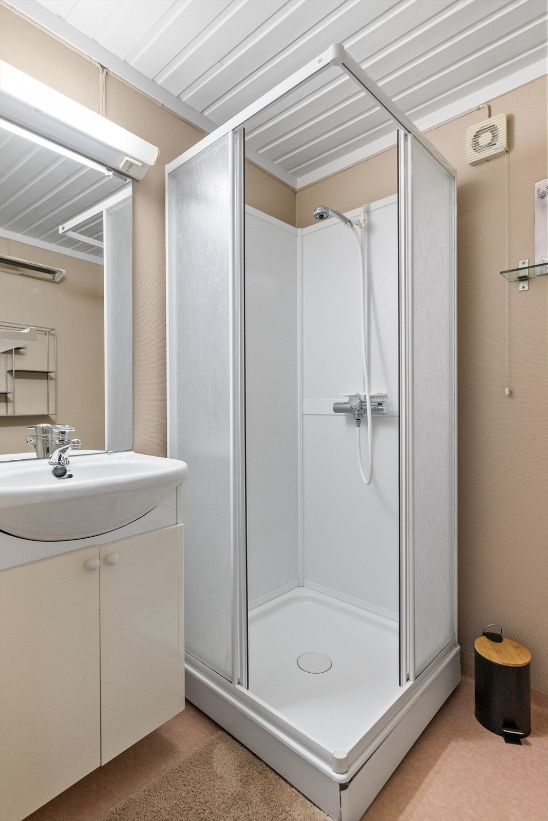 Badet inneholder innredning med servant, speil, gulvmontert toalett og dusjkabinett. Galleribilde