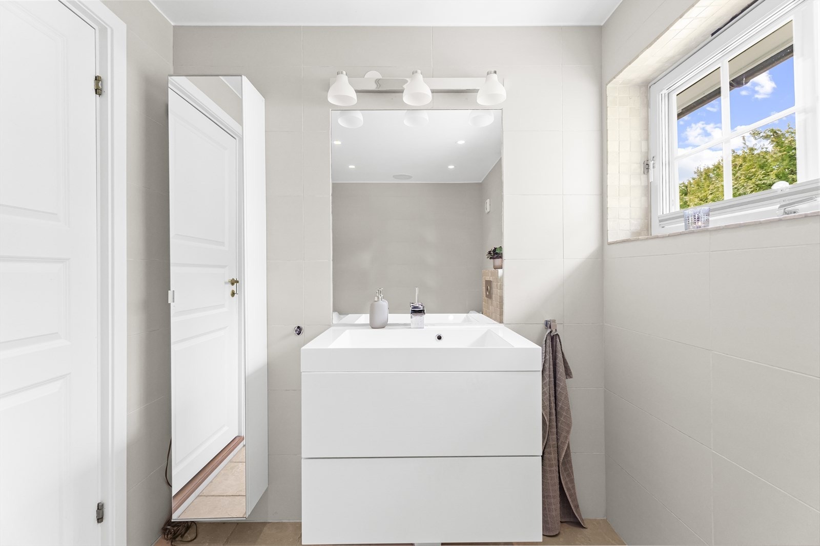 Videre har badet skap med glatte fronter, speil og servant. Galleribilde