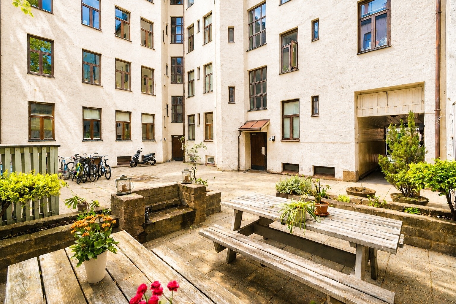 Felles bakgård med hyggelige oppholdssoner og beplantning mellom klassiske bygårdsfasader Galleribilde