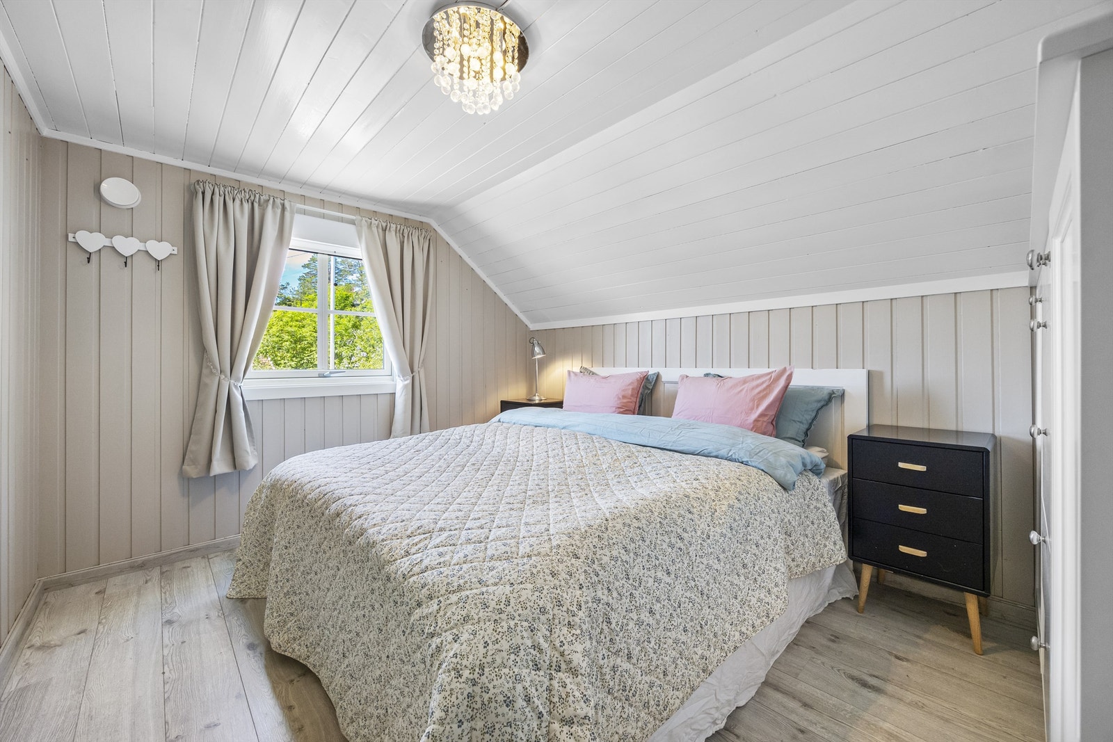 Boligens andre soverom på loftet, med laminat på gulvet og malt panel. Galleribilde