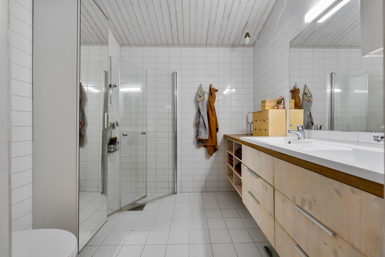 Badet er utstyrt med varmekabler i gulvet, servant med god oppbevaring og dusjhjørne med innfellbare dører. Galleribilde