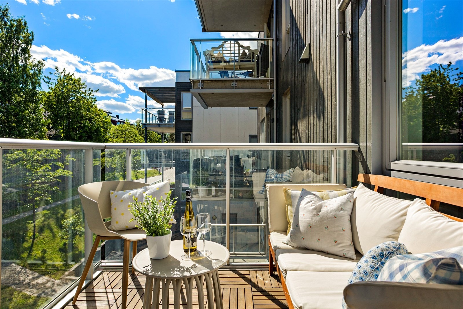 Balkongen har terrasseheller på betongdekke og et moderne rekkverk i aluminium og glass. Galleribilde