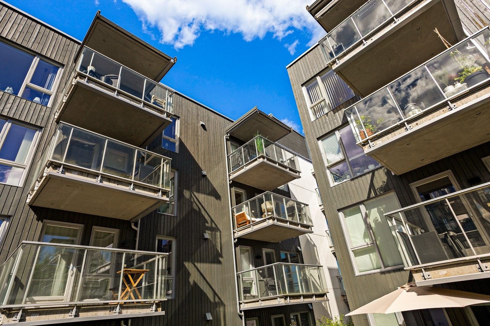 Bygningen har en moderne arkitektur med en kombinasjon av trepanel, balkonger og store vindusflater. Galleribilde