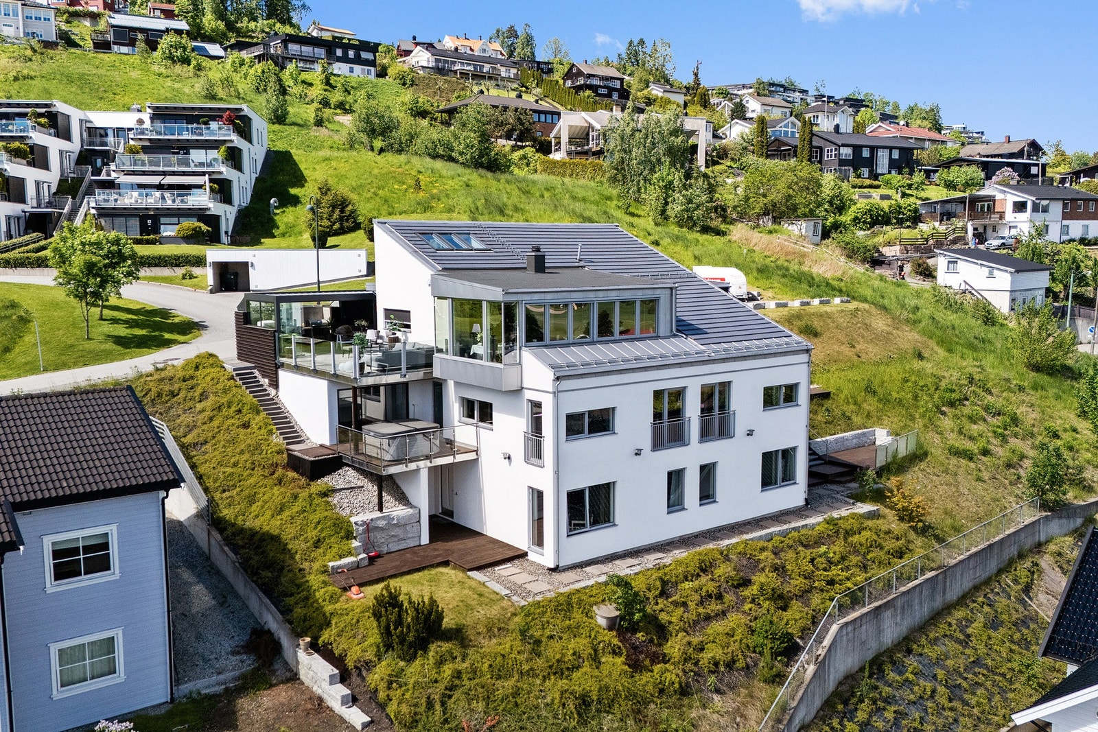 Tomten er meget pent opparbeidet i flere nivåer med støttemurer, terrasseplattinger og diverse beplantning Galleribilde