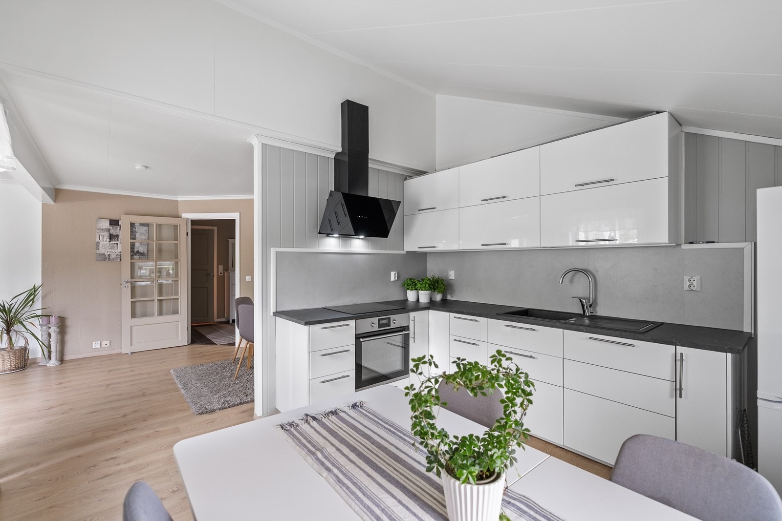 Kjøkkeninnredning fra 2017 med moderne og stilrent uttrykk med glatte fronter, laminatbenkeplate og integrerte hvitevarer som platetopp, komfyr og oppvaskmaskin. Galleribilde