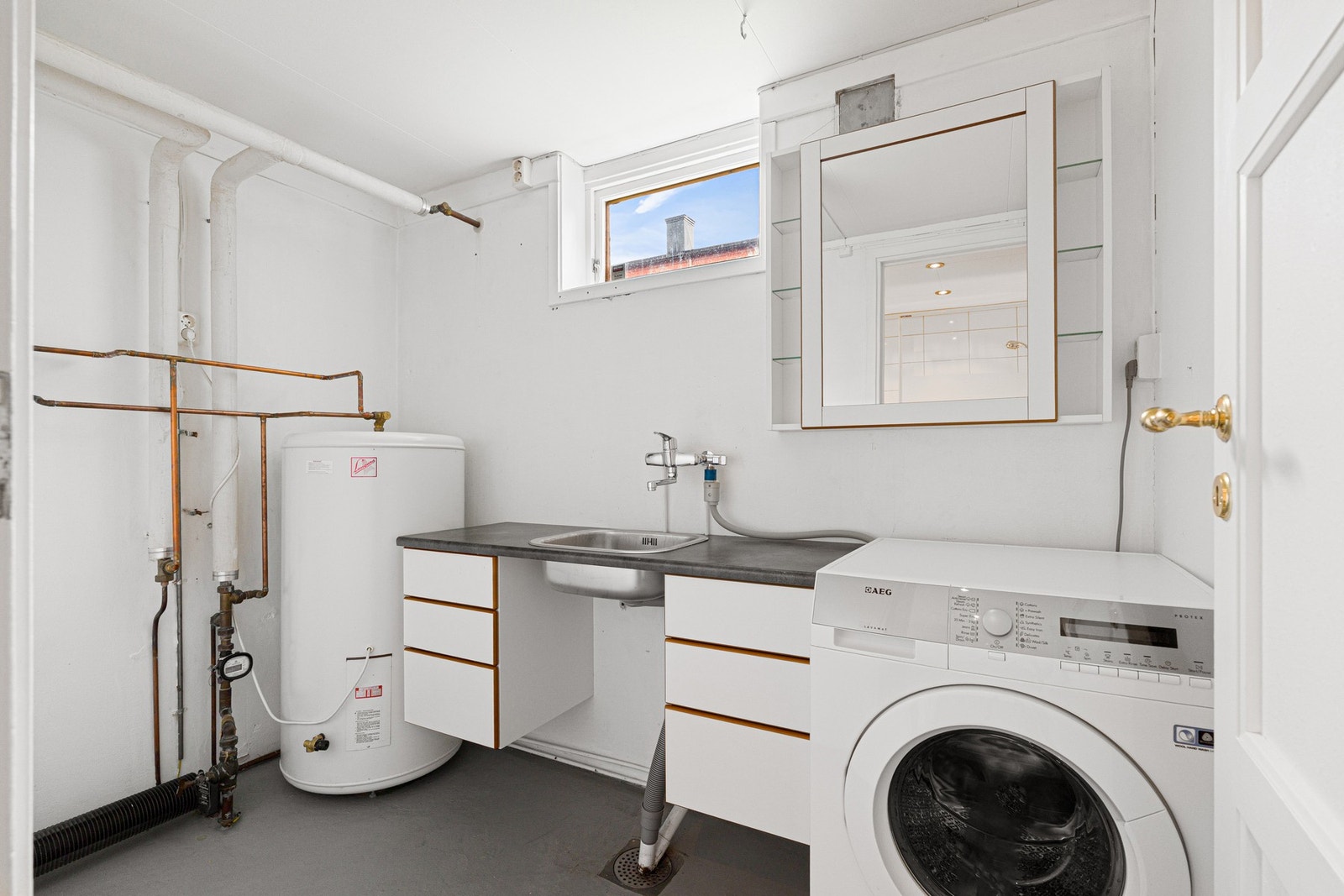 Eget vaskerom utstyrt med opplegg for vaskemaskin, varmtvannsbereder og utslagsvask. Galleribilde